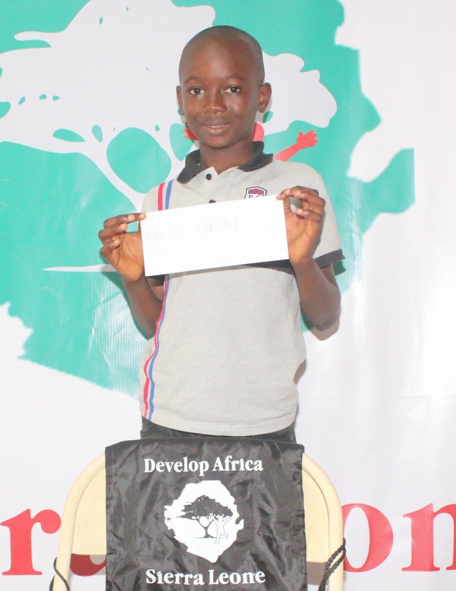 smiling boy in Africa, holding an envelop, with Develop Africa string bag, child sponsorship