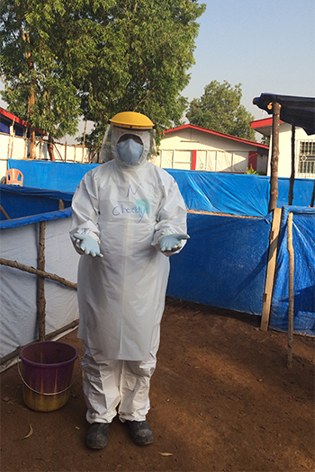 Nursing professor poses in full protective gear, including face shield, mask, gown and multiple pairs of gloves