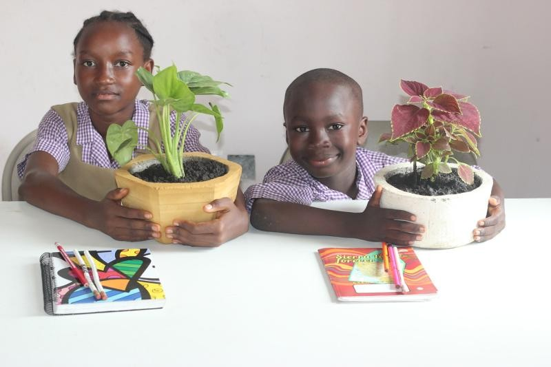 (c) Develop Africa. Children with flowers in pot ready for repotting