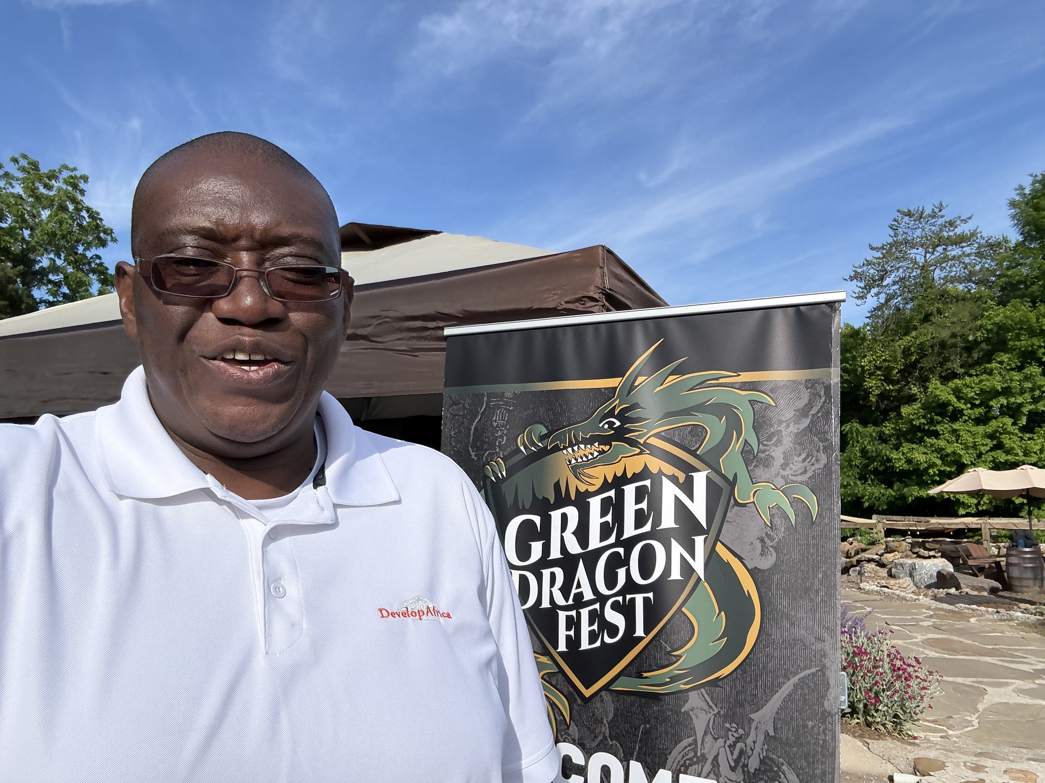 Sylvester standing beside the Green Dragon Fest Standing Banner