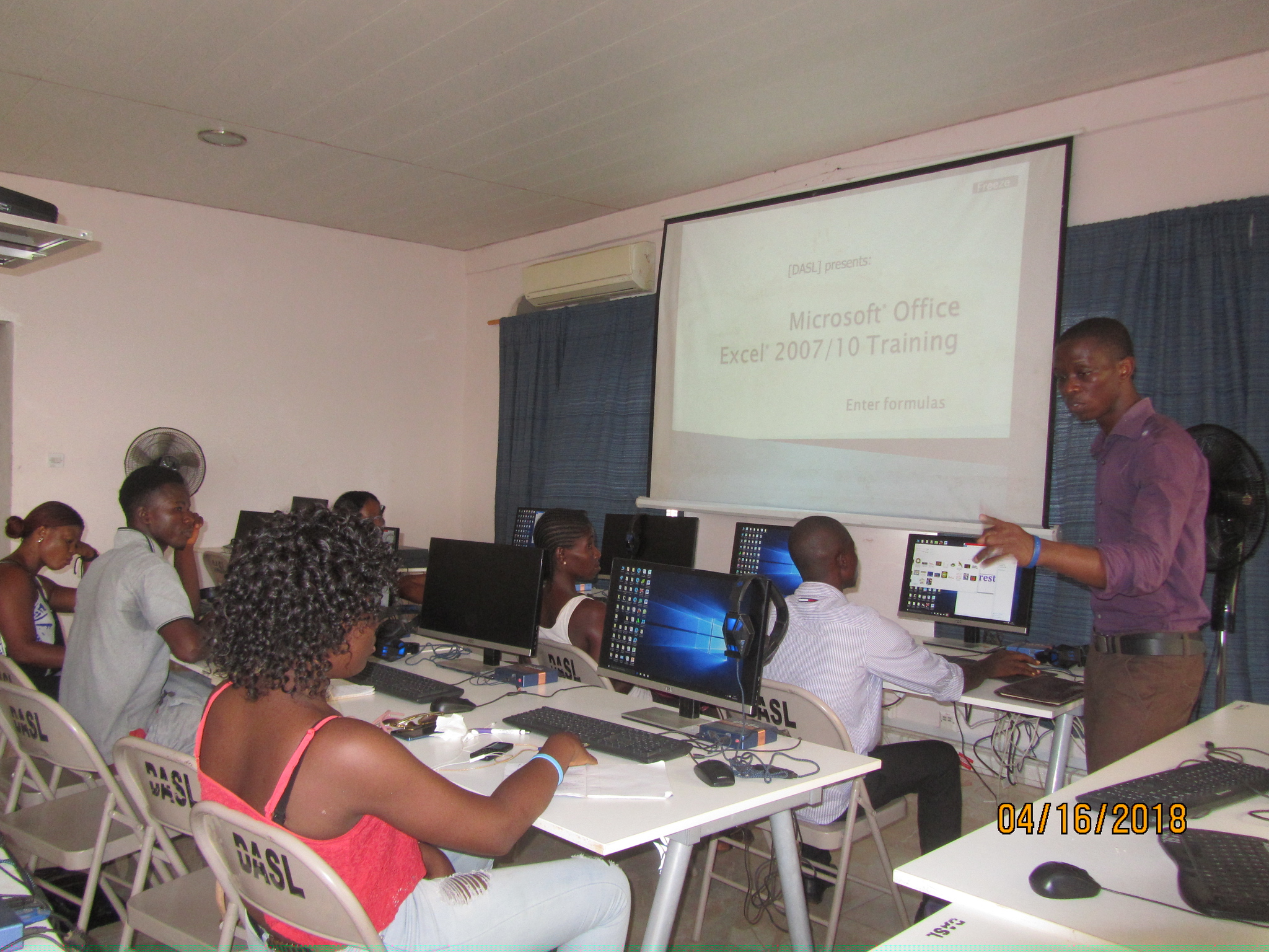 a-man-standing-in-front-of-youths-teaching-microsoft-office