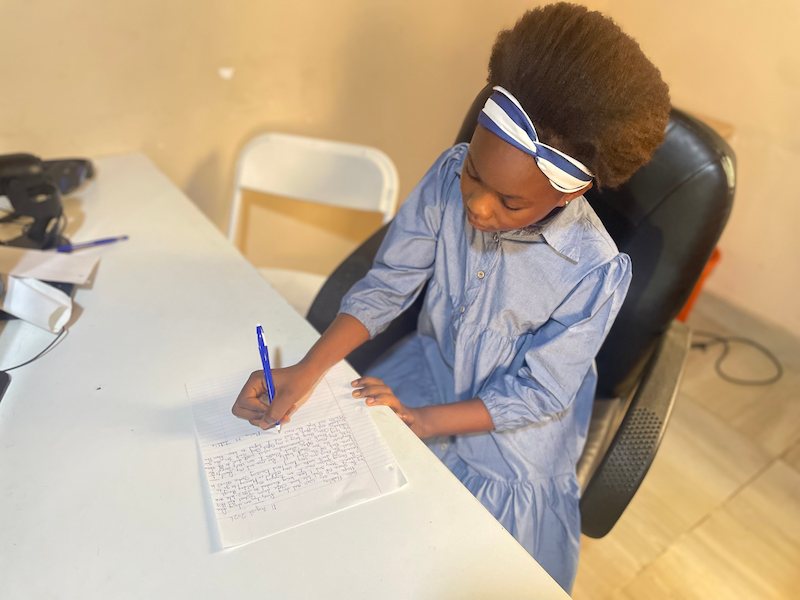 Marina writing a letter to her sponsor, Develop Africa, 2026
