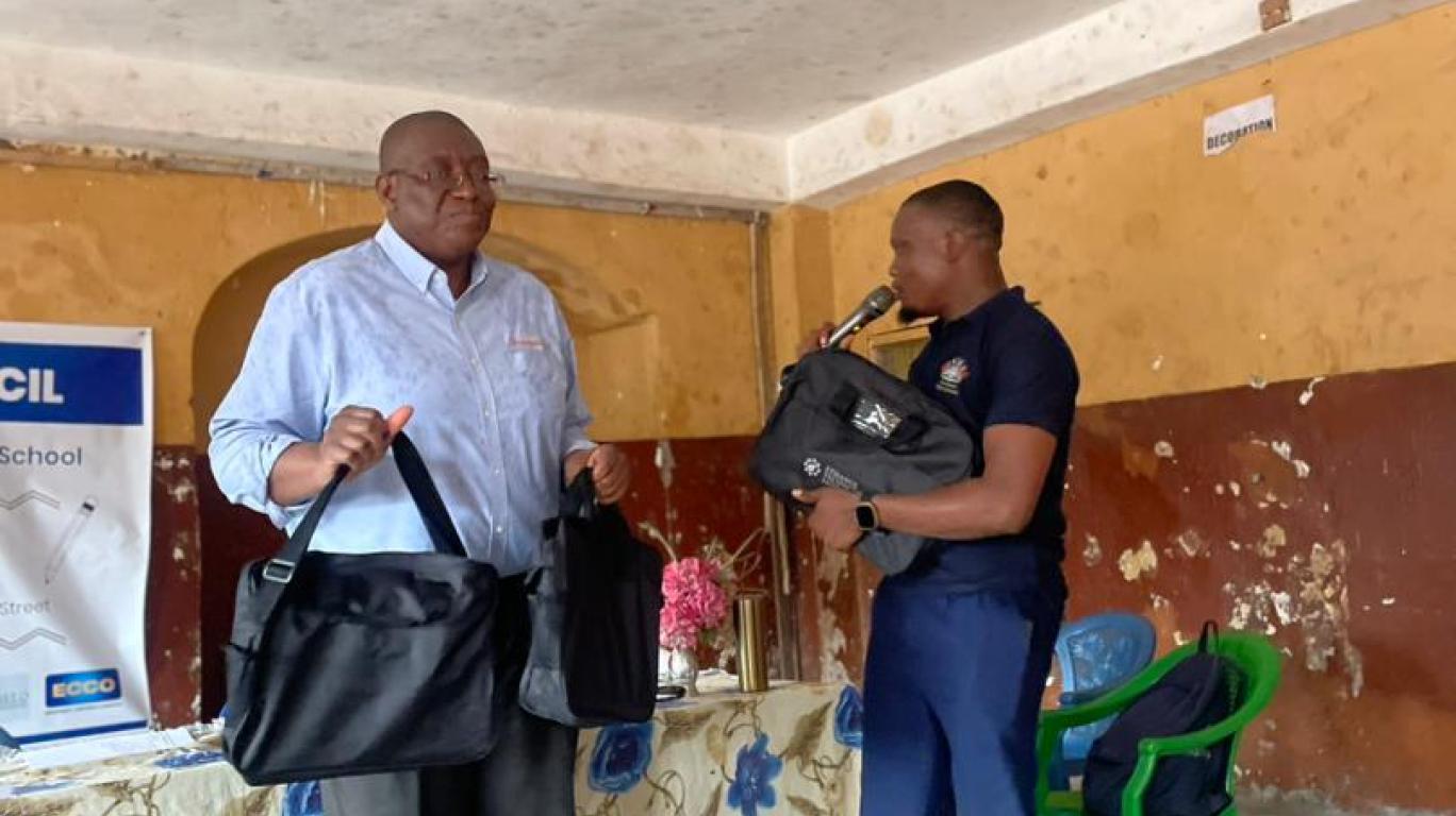 Sylvester Renner presenting laptops to Collins Pearce - representative of FCC Education Department