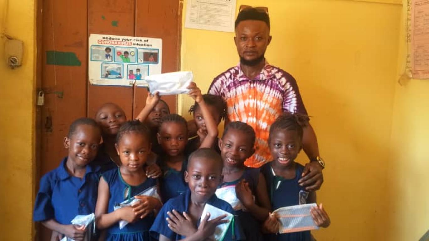 A Volunteer with students who recently received pencils