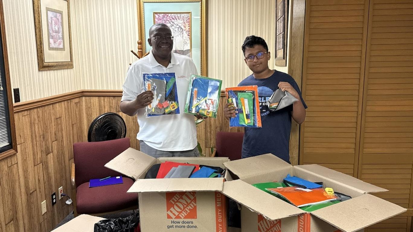 Aharshi with Sylvester - school supplies drop off at Develop Africa's office