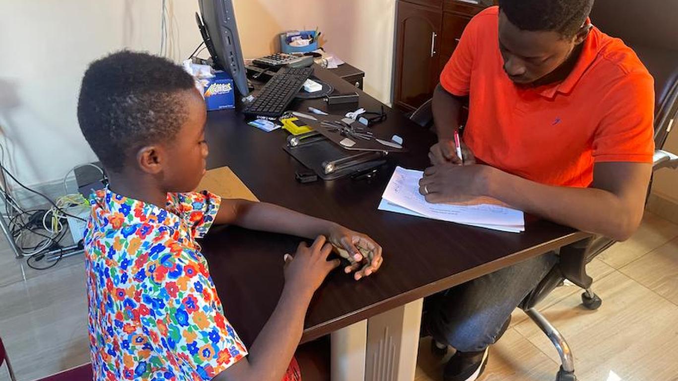 Joseph reviewing a beneficiary's report sheet, Sierra Leone, 2026