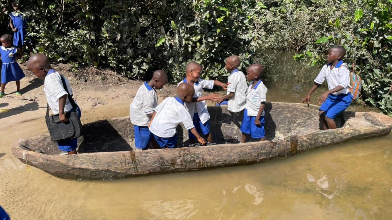 Children crossing the river to go to school in a canoe in Magbaikoli village