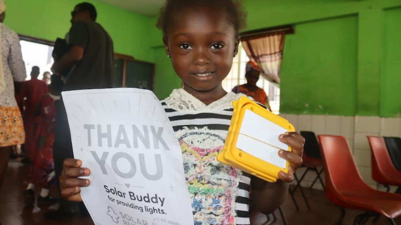 Kid with SolarBuddy lamp and a note - Sierra Leone July, 2026