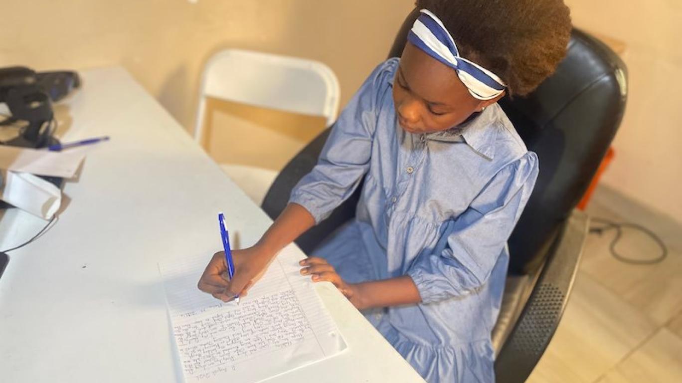Marina writing a letter to her sponsor, Develop Africa, 2026