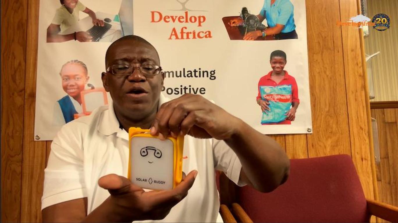 Sylvester Renner, Founder and President of Develop Africa Holding A Solar Buddy Lamp