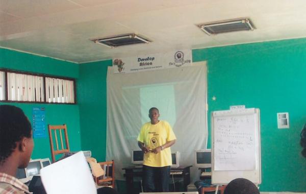 Sylvester - President & Founder of Develop Africa in a yellow T-Shirt in front of a training room in the early days of Develop Africa 