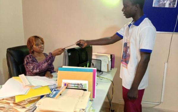 Aminata receiving a beneficiary's report sheet, Develop Africa, 2026
