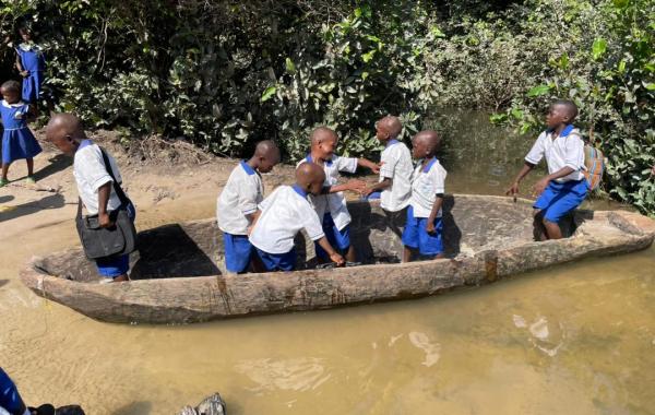 Children crossing the river to go to school in a canoe in Magbaikoli village