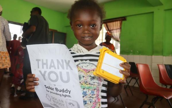 Kid with SolarBuddy lamp and a note - Sierra Leone July, 2026