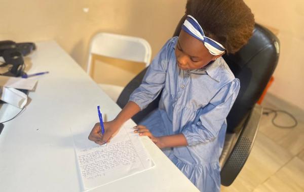 Marina writing a letter to her sponsor, Develop Africa, 2026