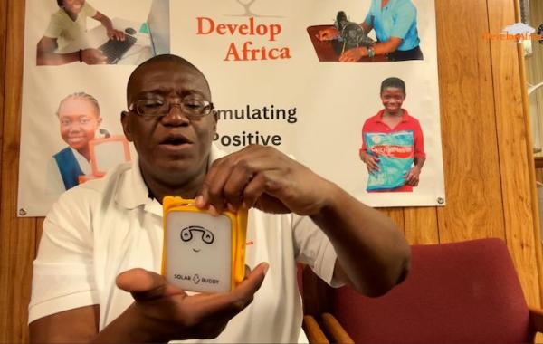 Sylvester Renner, Founder and President of Develop Africa Holding A Solar Buddy Lamp