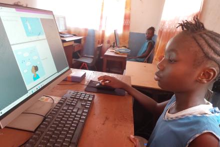 Aminata reading "Colors of the Rainbow" on her computer
