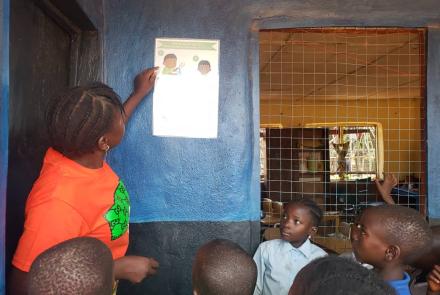 Kamawornie teacher showing students the steps to washing their hands on the poster