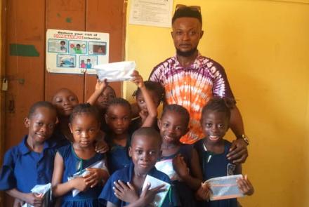 A Volunteer with students who recently received pencils