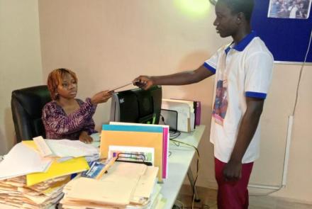 Aminata receiving a beneficiary's report sheet, Develop Africa, 2026