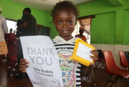 Kid with SolarBuddy lamp and a note - Sierra Leone July, 2026