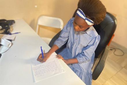 Marina writing a letter to her sponsor, Develop Africa, 2026